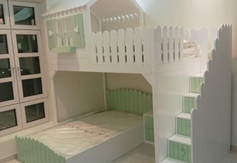 A bunk bed with a hut at the top and a fence that resembles a garden fence