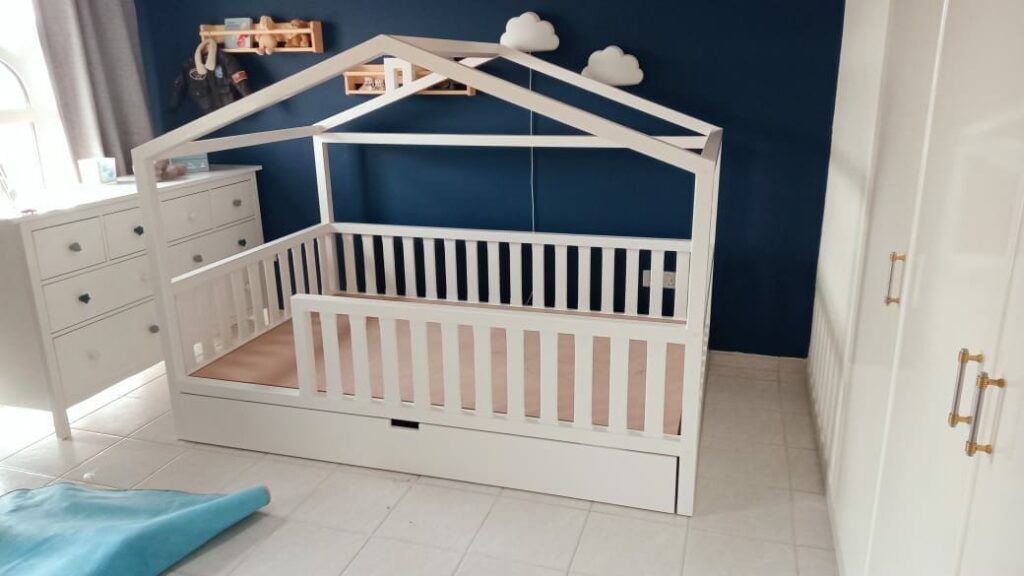 Bed with guardrails and storage drawer underneath, and has a wooden top like a cottage