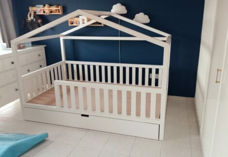 Bed with guardrails and storage drawer underneath, and has a wooden top like a cottage